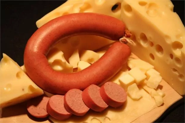 Sliced Trail Bologna ring with cheese and mustard on a rustic wooden board